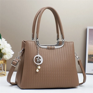 Detail view of brown textured leather handbag featuring silver crescent and star pearl charm