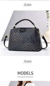 Dettaglio della trama goffrata vintage e del logo metallico sulla borsa nera chic