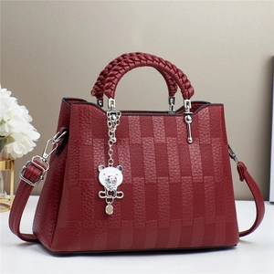 Detail of red checked handbag with woven handle and metallic bear charm accessory