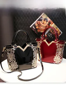 Détail de sacs à main luxe en cuir verni avec broderie dorée et fermoir en V métallique