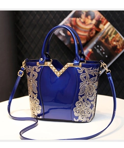 Détail du sac en cuir verni bleu avec paillettes florales dorées et rivets en métal