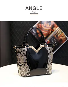 Gros plan d'un sac à main en cuir verni noir avec broderies florales en paillettes dorées