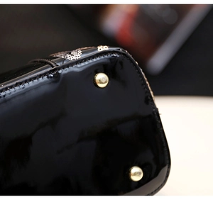 Détail de la base du sac en cuir verni noir avec clous dorés et coutures de haute précision