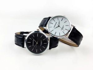 Macro shot of silver quartz watch set with roman numerals and black embossed leather strap