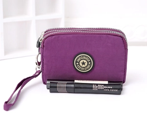 Detail of purple nylon phone bag with triple zippers and star logo on white stand