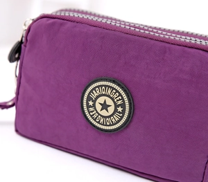 Dettaglio della trousse in nylon viola con tripla cerniera e materiale testurizzato