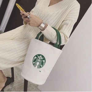Detail of white canvas tote bag with green handles and iconic green logo print