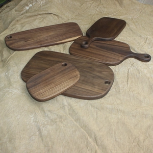 Solid black walnut wood bread boards in various shapes with handles for hanging storage