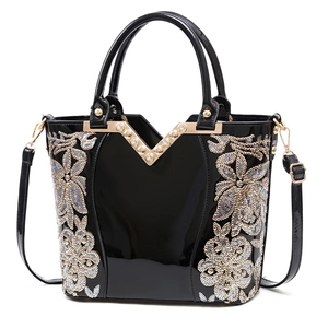 Sac à main élégant en cuir verni noir avec broderies florales dorées et bordure en V