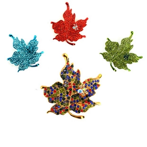 Detailed view of four colorful maple leaf brooches with gold plating and rhinestones