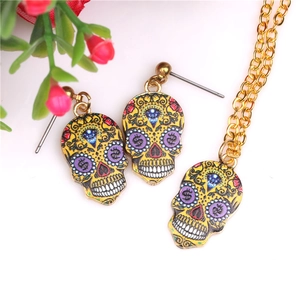 Macro shot of colorful gold sugar skull necklace and earrings set with dollar sign eyes