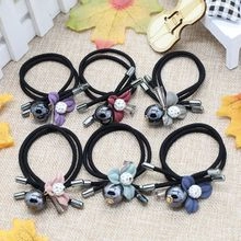 Dettaglio di 6 elastici per capelli con fiori in seta e perline a pois su sfondo beige