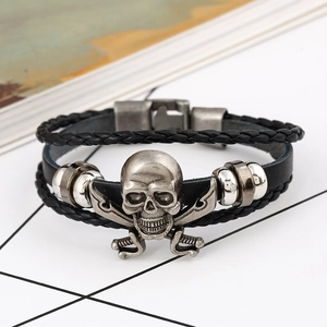 Macro shot of punk style black leather bracelet featuring a silver skull and crossbones charm