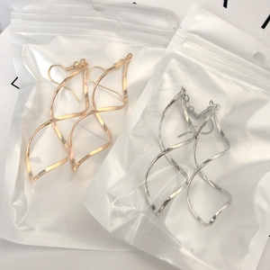 Macro shot of minimalist spiral wave earrings in gold and silver finish packaging