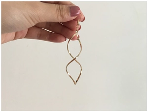 Macro shot showing the size and golden twisted spiral curves of long dangle earrings