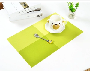 Close-up of green woven Teslin placemat on a white table with elegant home decor