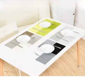 Close-up of heat-resistant woven PVC placemats in four colors with cutlery on a table