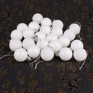 Macro shot of white Christmas balls in glossy, matte, and glitter finishes with silver strings