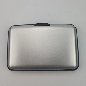 Close-up of silver brushed aluminum card holder with a black push-button locking mechanism