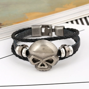 Macro detail of multi-layer black leather bracelet with vintage silver skull charms
