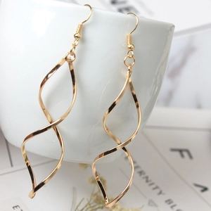 Macro shot of gold double spiral wave drop earrings showing polished metallic texture