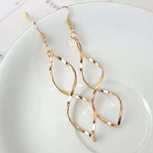 Minimalist gold spiral drop earrings with curved wave design on a white ceramic tray