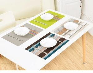 Close-up of four assorted PVC woven placemats with plates and cutlery on a white table