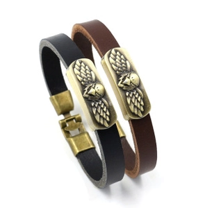 Detail view of woven leather bracelets with vintage brass eagle crest and metal clasps