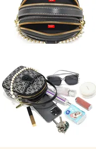 Detail view of round crossbody bag showing multi-layer zippers and spacious interior