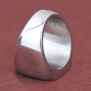 Close-up of a square polished stainless steel ring on red textured fabric