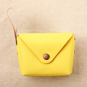 Detail of yellow macaron coin purse with bronze snap button and slender leather strap
