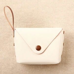 Detail of cream envelope coin purse with vintage bronze snap button and wrist strap