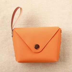 Detail of vibrant orange leather coin purse with bronze snap button on burlap background