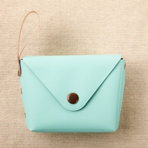 Top view of a mint green envelope coin purse in synthetic leather with retro button