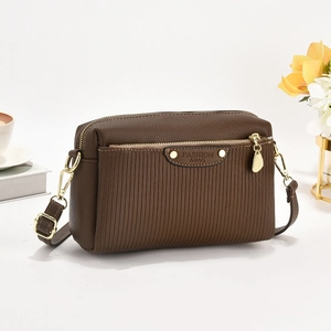 Détail d'un sac bandoulière marron rayé avec finitions dorées et étiquette cuir