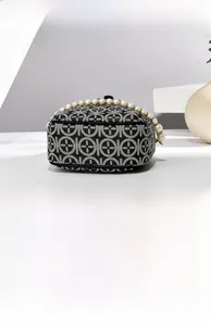 Detail view of the black and white geometric fabric handbag with elegant pearl handle