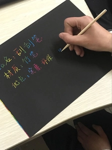 Bamboo scratch pen tool revealing vibrant rainbow colors on black scratch art paper