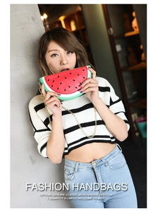 Detail view of watermelon-shaped crossbody bag with gold chain strap and leather stitching