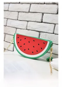 Detail of watermelon-shaped crossbody bag with red and green panels and gold chain strap