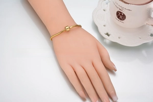 Detail of 316L gold snake chain bracelet with barrel clasp on a model wrist