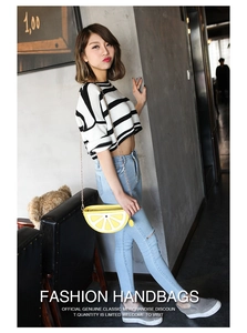 Detailed view of yellow lemon-shaped crossbody bag with gold chain strap on model
