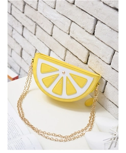 Detail view of lemon slice crossbody bag with golden chain strap on a white table
