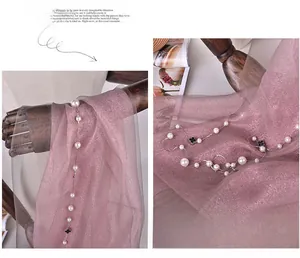Detailed macro view of pink silk organza scarf featuring pearl strings and clover charms.