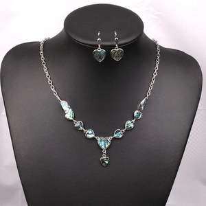 Detail of bohemian heart jewelry set with iridescent shell inlay on a black display stand