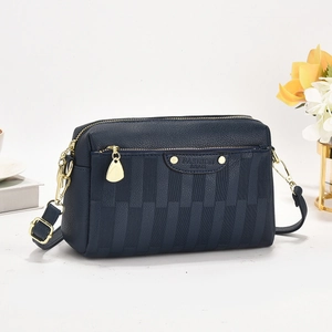 Dark blue textured leather crossbody bag with gold hardware and stylish stripe paneling
