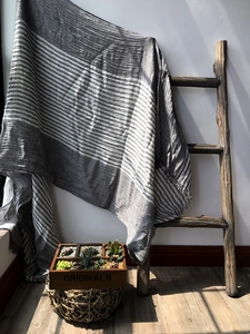 Detail of gray striped cotton scarf draped on a wooden ladder with rustic succulents