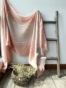 Detailed view of pink and white striped cotton scarf with fringe on a wooden ladder