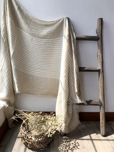 Close-up of striped cotton shawl with fringe detail hanging on vintage wooden ladder