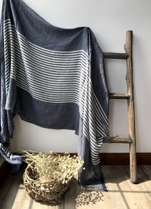 Detail of blue and white striped cotton scarf with fringe hanging on wooden ladder