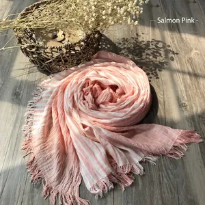 Orange pink striped cotton scarf with fringed edges on a rustic wooden background